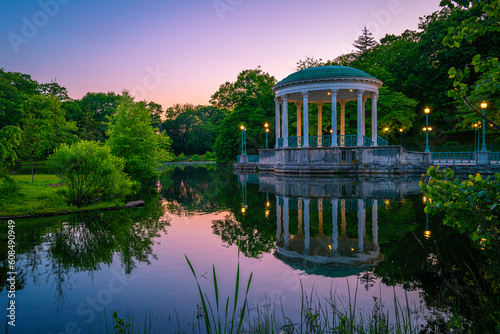 Bandstand Pavillion scenic spot landscape illuminated at sunset with water reflections on Roosevelt Lake at Roger Williams Park in Providence, Rhode Island