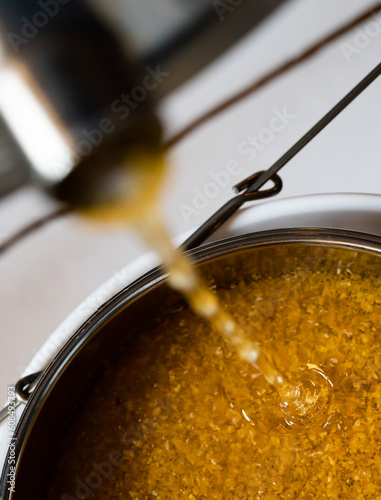 Billede på lærred Honey flowing out of an extractor and into a strainer during extraction