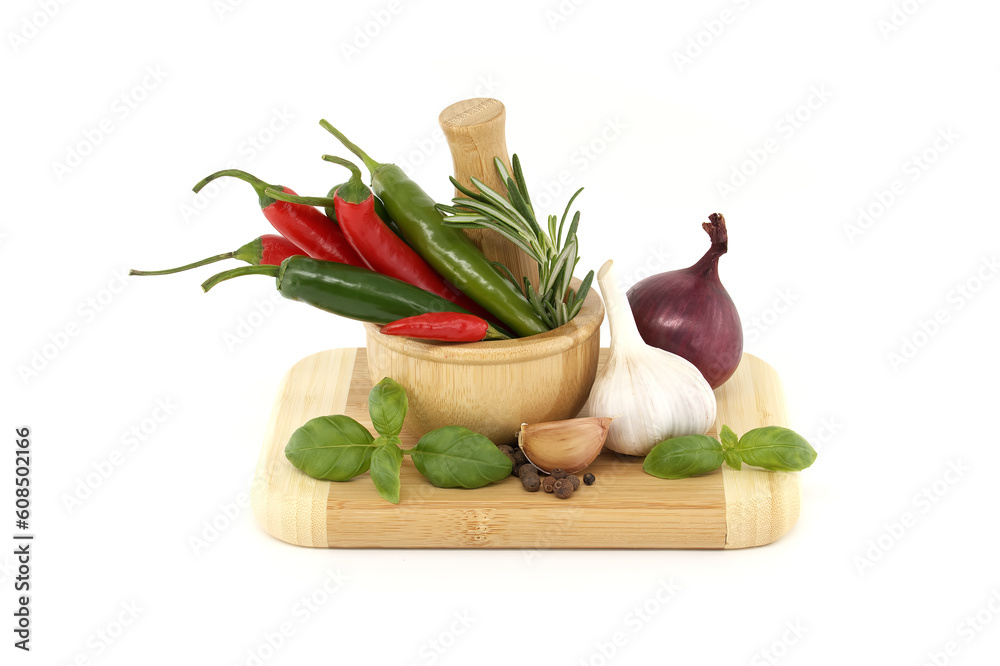 Chili peppers in wooden mortar and herbs over white Chili peppers in wooden mortar and herbs over white