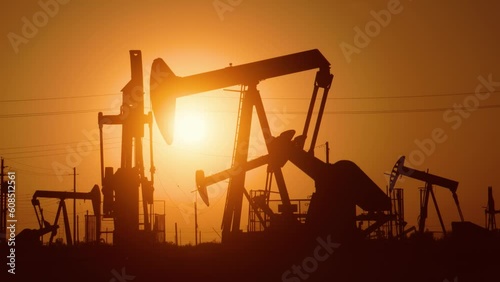 The sun rises behind a large oil field in California.