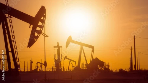 The sun rises behind a large oil field in California.