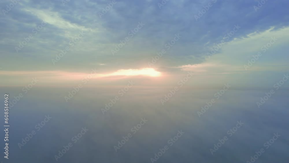 Sunrise in the fog from a drone in Africa. The low down clouds light up from the rising sun, with blue and gold colours. Humid landscape after the rain season Sunrise in the fog from a drone in Africa. The low down clouds light up from the rising sun, with blue and gold colours. Humid landscape after the rain season