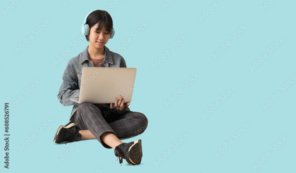 full body portrait young Happy Asian teenager girl siting holding laptop computer and sitting on the floor, isolated on pastel plain light blue background full body portrait young Happy Asian teenager girl siting holding laptop computer and sitting on the floor, isolated on pastel plain light blue background