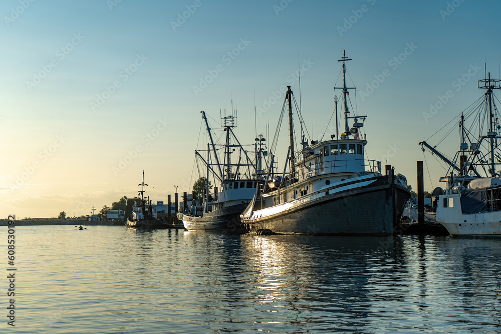 Fishing boats docked at harbor on sunny clear sky sunset