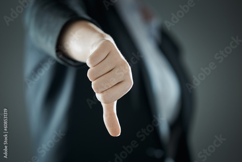 Female thumb down close-up on the background of suit in blur. Business concept. photo