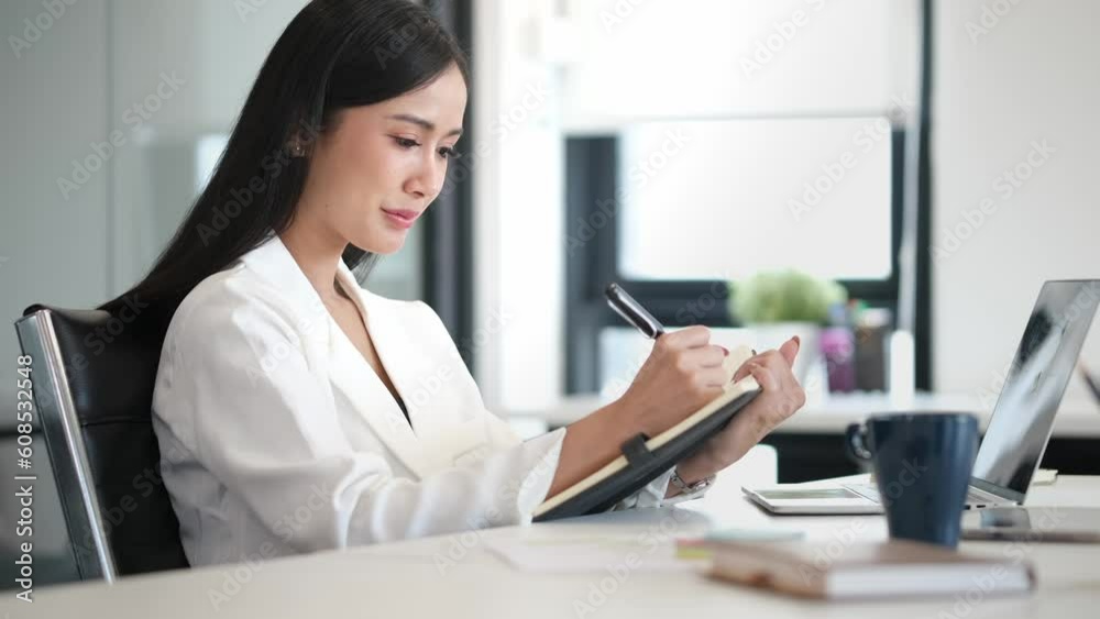 Beautiful businesswoman writing in notebook planning for startup company and marketing strategy and ideas. Beautiful businesswoman writing in notebook planning for startup company and marketing strategy and ideas.