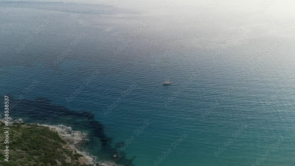 Boat moored in a beautiful bay with blue sea. Sardinia, Italy. Aerial backward view Boat moored in a beautiful bay with blue sea. Sardinia, Italy. Aerial backward view