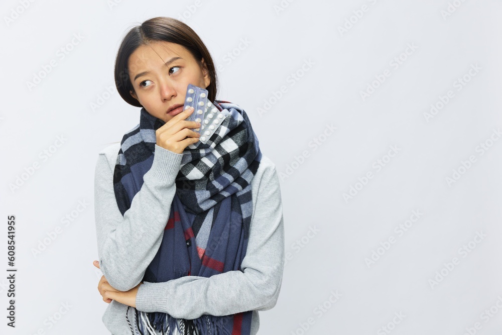 Asian woman headache cold flu holding medicine and pills in checkered plaid with fever sick of virus on white background, copy space Asian woman headache cold flu holding medicine and pills in checkered plaid with fever sick of virus on white background, copy space