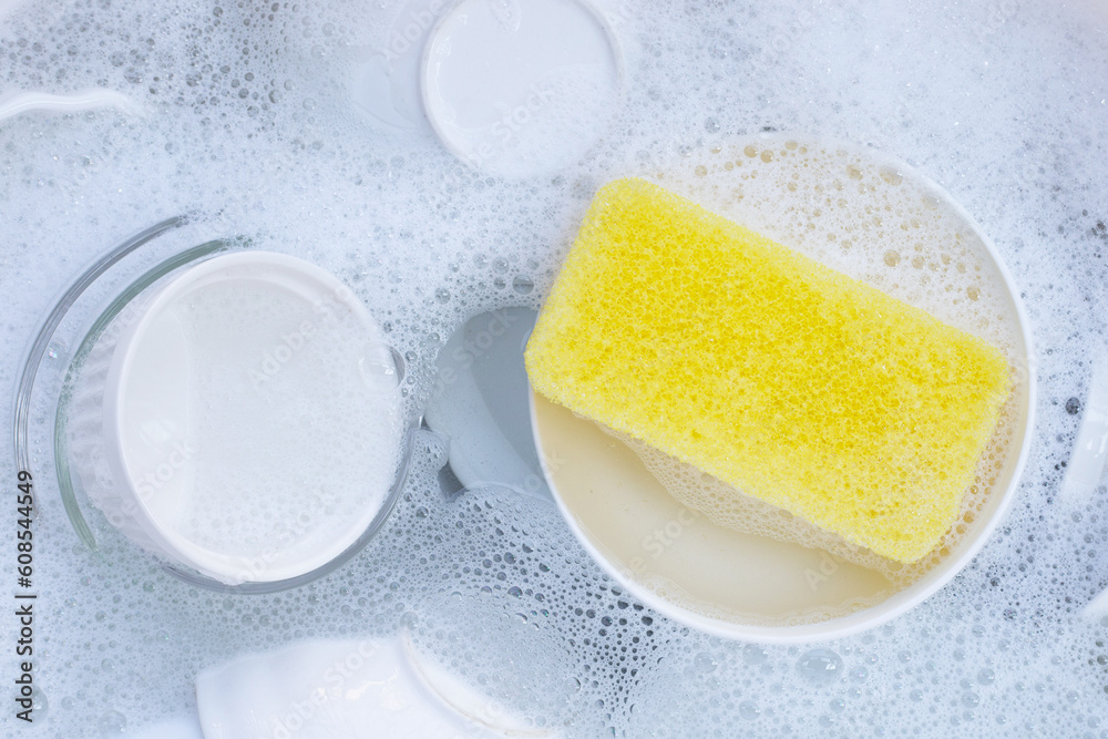 Dishes and bowls in water and bubbles of dishwashing liquid Dishes and bowls in water and bubbles of dishwashing liquid