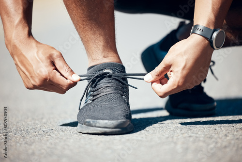 Man, hands and tie shoes on road for fitness, running exercise or cardio workout outdoors. Hand of male person, athlete or runner tying shoe getting ready for exercising or training on asphalt street