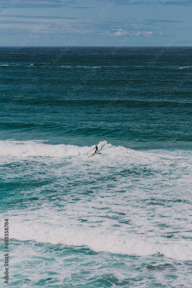 Wide vertical shot of a surfer riding the waves at Bondi Beach in Australia