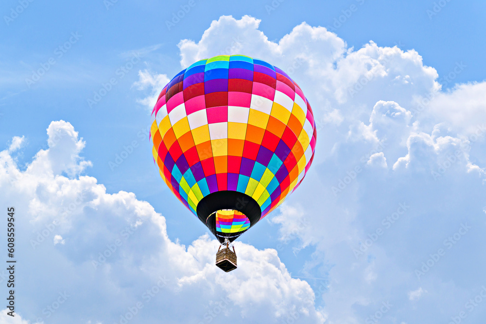 Naklejka premium Colorful hot air balloon flying over blue sky with white clouds