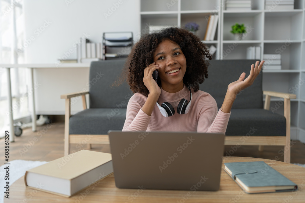 Young African American woman using mobile phone to attend online training Talk while learning via video call on laptop computer. Using headset. E-education, online class, training concept. Young African American woman using mobile phone to attend online training Talk while learning via video call on laptop computer. Using headset. E-education, online class, training concept.