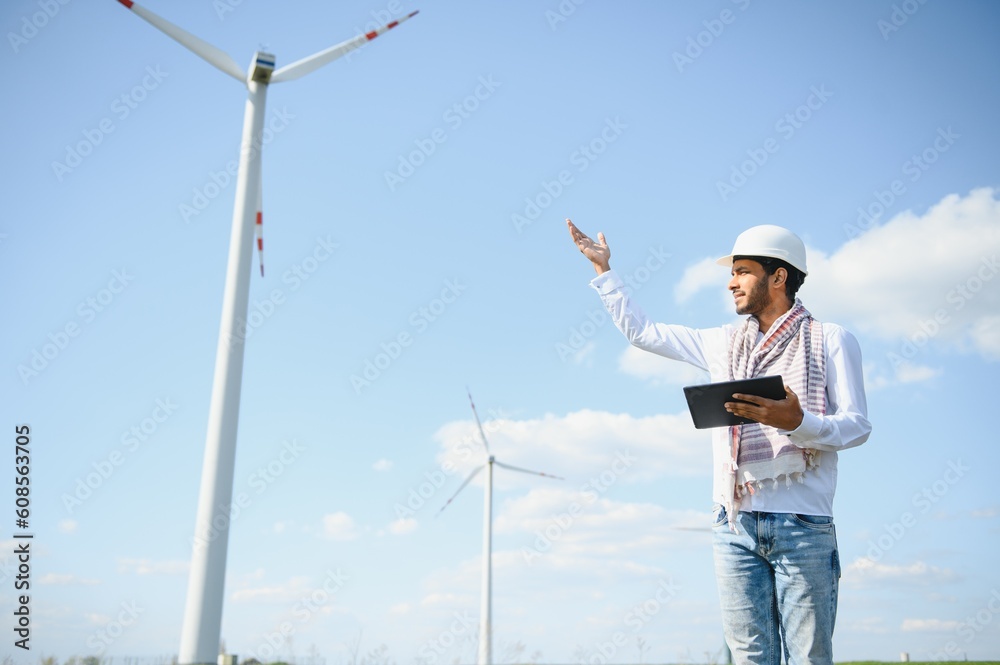 Portrait of focused indian man standing on field with wind turbines Portrait of focused indian man standing on field with wind turbines