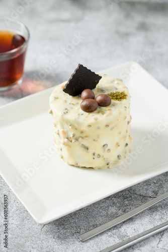 Single person mini cake with pistachio and white chocolate on a white porcelain plate