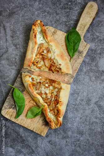  Traditional Turkish cuisine. Baked Pide dish with chicken ,  cheese and  herbs on  wooden background.  Turkish pizza pide