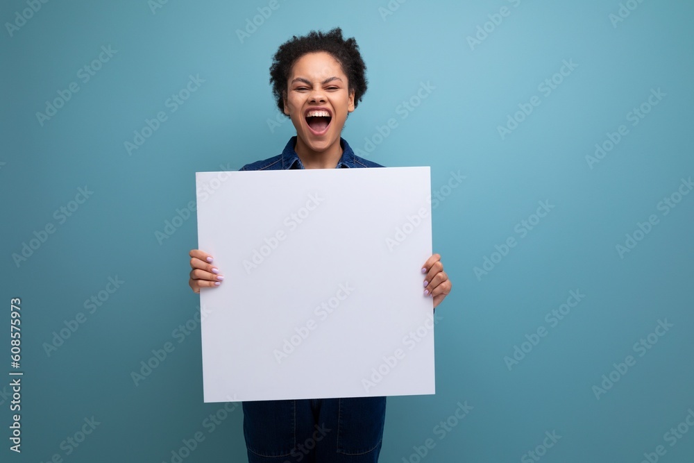 young pretty hispanic business woman with fluffy hair dressed in blue denim suit holding billboard with blank space young pretty hispanic business woman with fluffy hair dressed in blue denim suit holding billboard with blank space