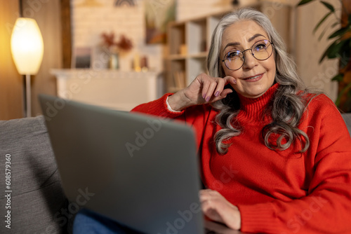 Cuadro en lienzo Long-haired pretty senior woman in eyeglasses with a laptop