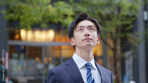 遠くを見つめるスーツを着た若い日本人ビジネスマンのスローモーションイメージ