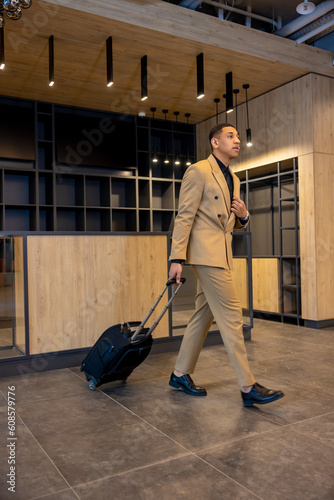 Young businessman in beige suit arriving to the hotel