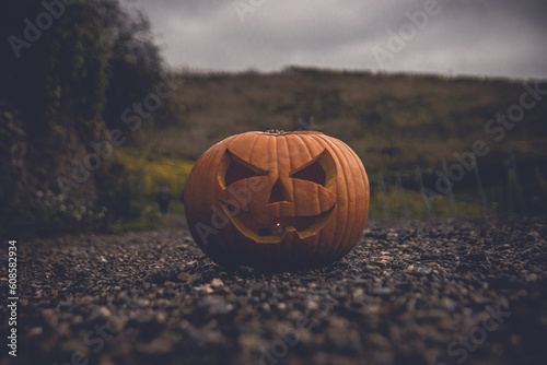 Halloween Jack-O-Lantern, frontal view. Pumpkin sitting on a lone path in the afternoon hours. Spooky atmospheric Halloween photo. photo