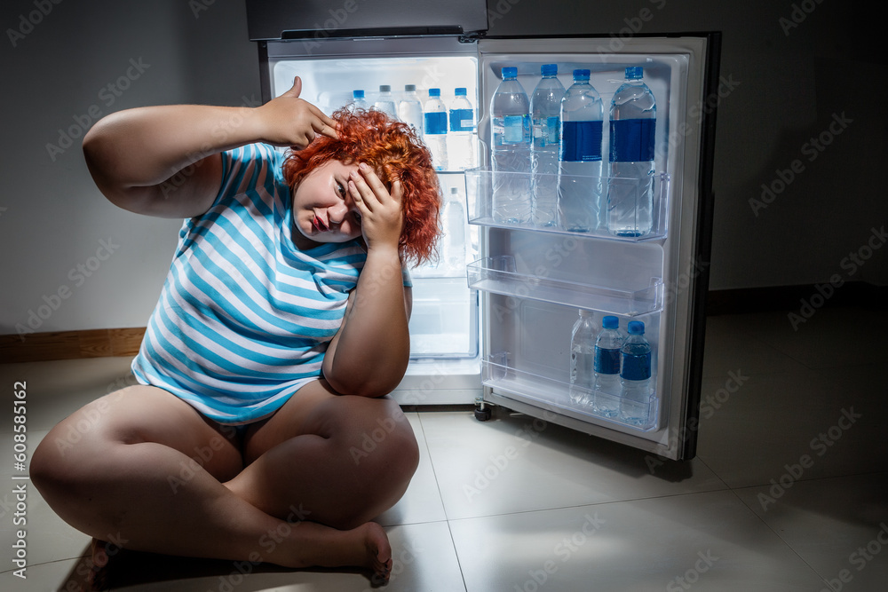 Obraz premium Photo at night of Overweight woman opening refrigerator and looking for a late supper.