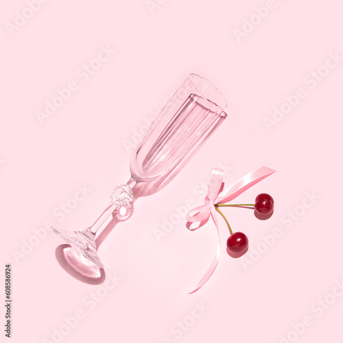 Champagne flute and cherry fruit, creative aesthetic retro romantic girly summer party concept, pastel pink background. © Biancaneve MoSt