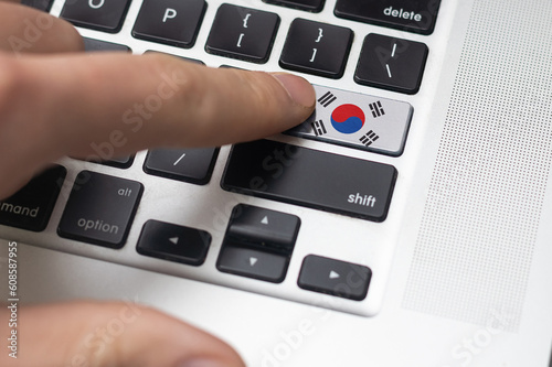 Male hand pressing keyboard button with flag of South Korea on it. Online international business concept.