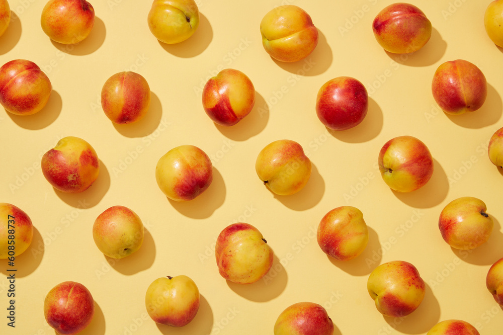 Colorful fruit pattern of fresh peaches (prunus persica) on yellow background. Creative background for advertising and branding for cosmetic or product with ingredient from peach Colorful fruit pattern of fresh peaches (prunus persica) on yellow background. Creative background for advertising and branding for cosmetic or product with ingredient from peach