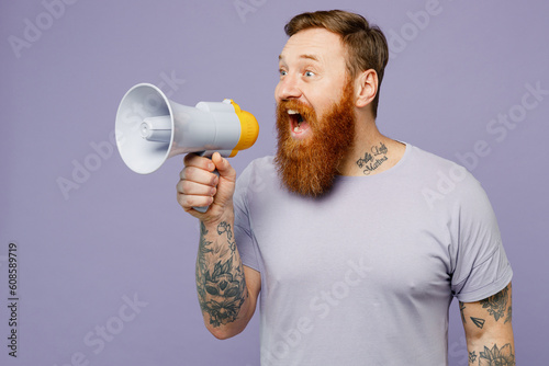 Young redhead bearded man wear violet t-shirt casual clothes hold in hand megaphone scream announces discounts sale Hurry up isolated on plain pastel light purple background studio. Lifestyle concept.