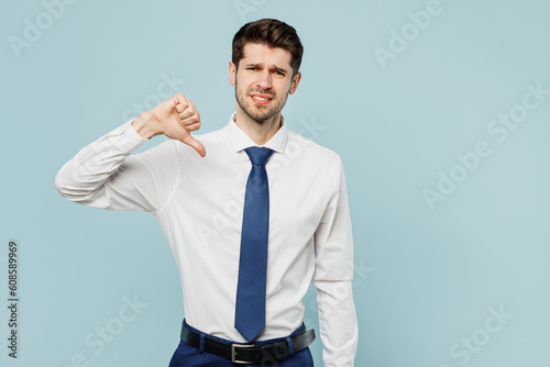 Tableau sur toile Young successful employee business man corporate lawyer wear classic formal shirt tie work in office showing thumb down dislike gesture isolated on plain pastel light blue background studio portrait