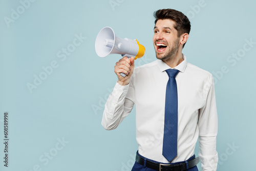 Young fun employee business man corporate lawyer wear classic formal shirt tie work in office hold megaphone scream announces discounts sale Hurry up isolated on plain blue background studio portrait.