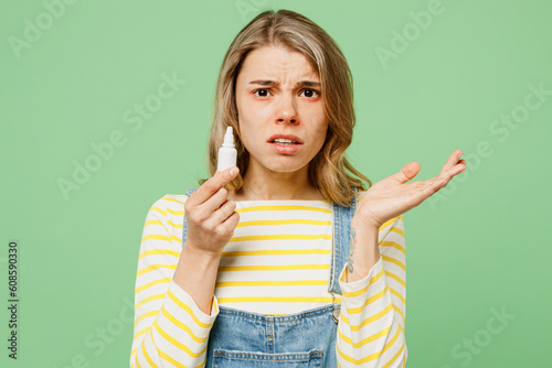 Sick unhealthy ill allergic sad woman has red watery eyes runny stuffy sore nose suffer from allergy trigger symptoms hay fever use nasal spray spread hand isolated on plain green background studio.