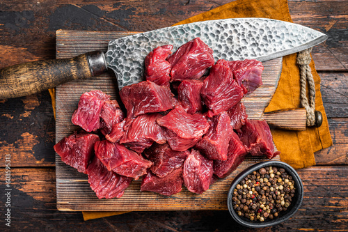 Sliced Raw venison dear meat for a stew, game meat on butcher cutting board. Wooden background. Top view photo