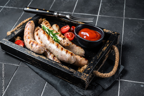 Grilled Bratwurst meat sausages with herbs and spices. Black background. Top view