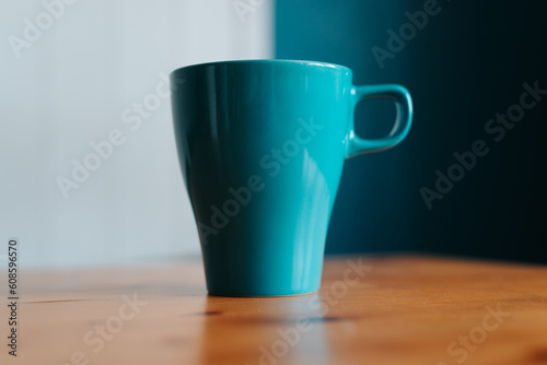Close-up of a blue mug on a wooden table indoors, selective focus on object