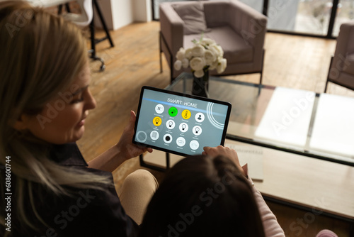 Woman controlling smart home devices using a digital tablet with launched application in the living room. Smart home concept