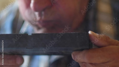 close-up of an elderly man blowing dust from an old video cassette, slow motion. selective focus. old home video archives. vintage video cassette in the dust photo