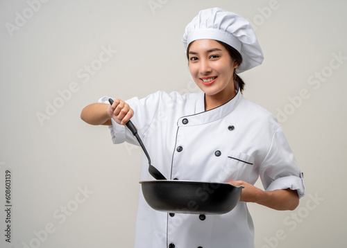 Young beautiful asian woman chef in uniform holding turner and iron Frying pan utensils cooking in the kitchen various gesture on isolated background. woman occupation chef restaurant and hotel. photo