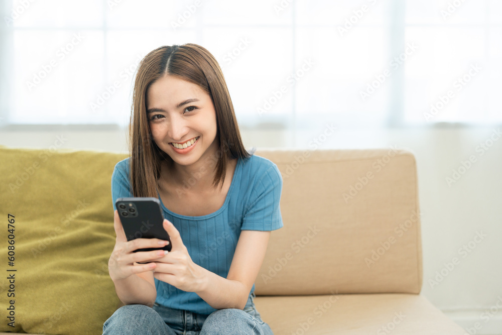 Asian woman using smartphone. Chatting video conference online sitting sofa in living room at home. Business Woman Shopping online store. Relax time at home Asian woman using smartphone. Chatting video conference online sitting sofa in living room at home. Business Woman Shopping online store. Relax time at home