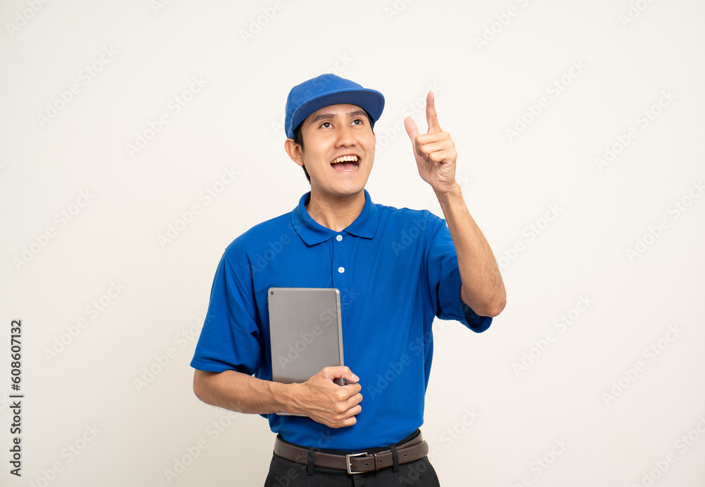 Asian man in blue uniform standing holding digital tablet computer on isolated white background. Male service worker with cell phone. Delivery courier shipping service Asian man in blue uniform standing holding digital tablet computer on isolated white background. Male service worker with cell phone. Delivery courier shipping service