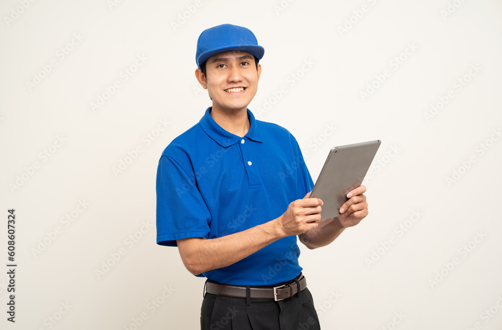 Asian man in blue uniform standing holding digital tablet computer on isolated white background. Male service worker with cell phone. Delivery courier shipping service Asian man in blue uniform standing holding digital tablet computer on isolated white background. Male service worker with cell phone. Delivery courier shipping service