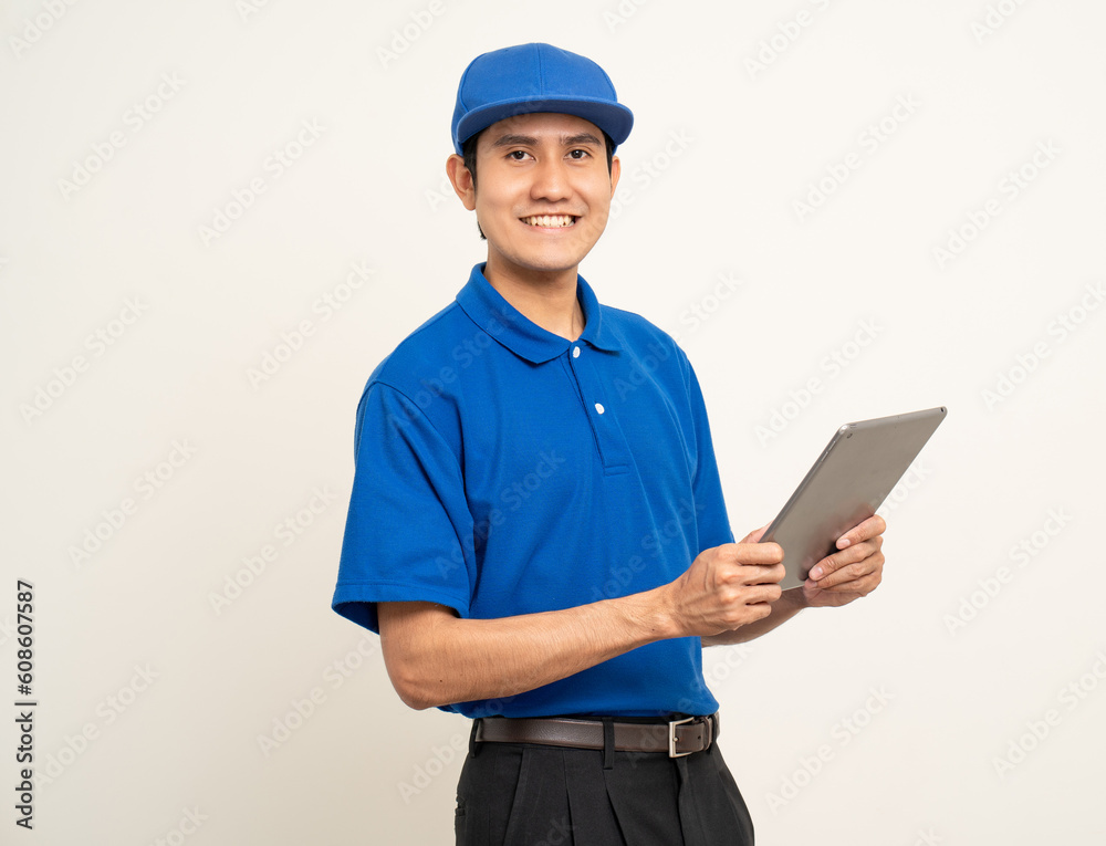 Asian man in blue uniform standing holding digital tablet computer on isolated white background. Male service worker with cell phone. Delivery courier shipping service Asian man in blue uniform standing holding digital tablet computer on isolated white background. Male service worker with cell phone. Delivery courier shipping service