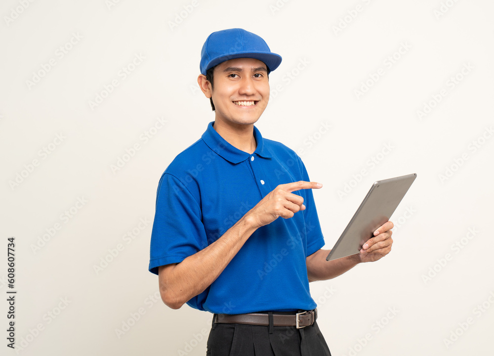 Asian man in blue uniform standing holding digital tablet computer on isolated white background. Male service worker with cell phone. Delivery courier shipping service Asian man in blue uniform standing holding digital tablet computer on isolated white background. Male service worker with cell phone. Delivery courier shipping service