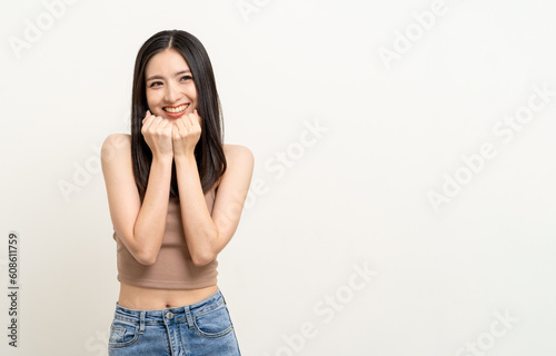 Beautiful smiling happy young asian woman age around 25 in brown shirt. Charming female lady standing pose on isolated white background. Asian cute people looking camera confident with white backdrop. © Chanakon