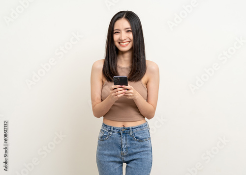 Pretty young asian woman using smartphone standing on isolated white background. Excited Beautiful young asian shopping online payment with mobile phone. Playing game on smartphone