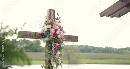 close up of wedding altar with a cross, pink and white flowers and greenery photo