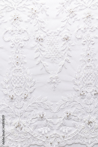 Vertical white background of bridal lace with beads and pearls on white satin fabric.. Wedding layout for design.