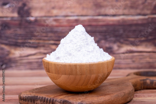 Powdered sugar on wooden background. Powdered or icing sugar in wood bowl