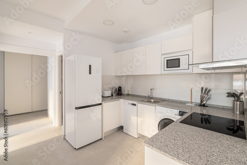 White stylish kitchen with modern appliances refrigerator washing machine and stove for cooking. Concept of a comfortable multifunctional kitchen after renovation